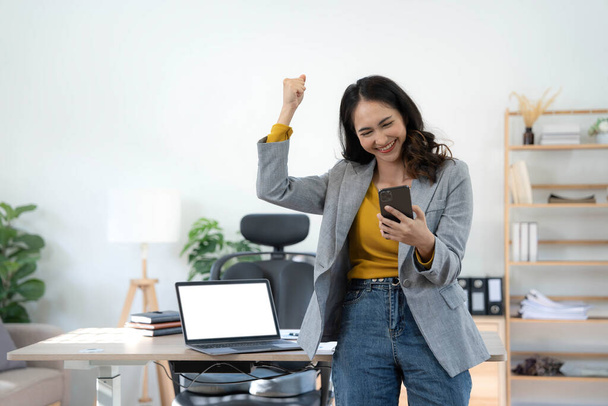 Feliz emocionado mujer asiática celebrar con ordenador portátil, el éxito o la acción feliz. Freelancer o Empresario utilizando la tecnología y poner en marcha el hogar moderno - Foto, imagen