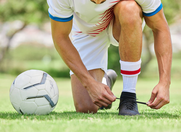 スポーツ、サッカー、男はフィールドに靴を結び、試合、試合、屋外トレーニングの準備ができています。フィットネス、運動、サッカー選手は良いパフォーマンスのためにサッカー場でトレーニングする前にスニーカーに靴ひもを結ぶ. - 写真・画像