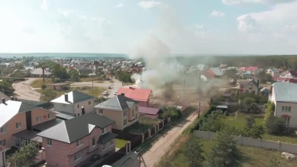 ドローンからの空中ビデオ映像。住宅地への飛行。灰色の煙がコテージから出ています。火事だ。道路だ。高品質4k映像 - 映像、動画