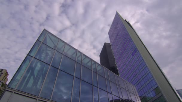 Wolken worden weerspiegeld in een spiegelglazen wolkenkrabber in een zakenwijk. Zakelijk bedrijf, hoge wolkenkrabber glazen oppervlak. Tijd verstrijkt. Hoge kwaliteit 4k beeldmateriaal - Video