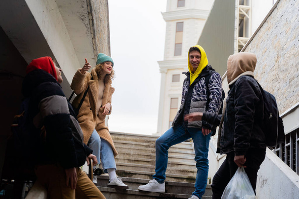 Group of amazing and attractive friends are having a discussion on the stairs while laughing - Foto, afbeelding