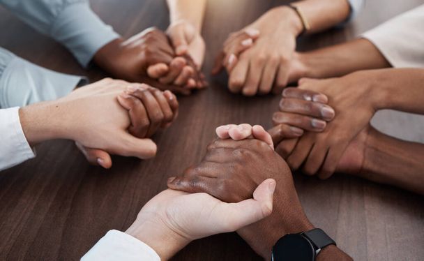 People, holding hands and care in diversity for trust, unity or community support together on a table. Hands of diverse group in collaboration for teamwork, meeting or social circle in hope at work. - Фото, изображение