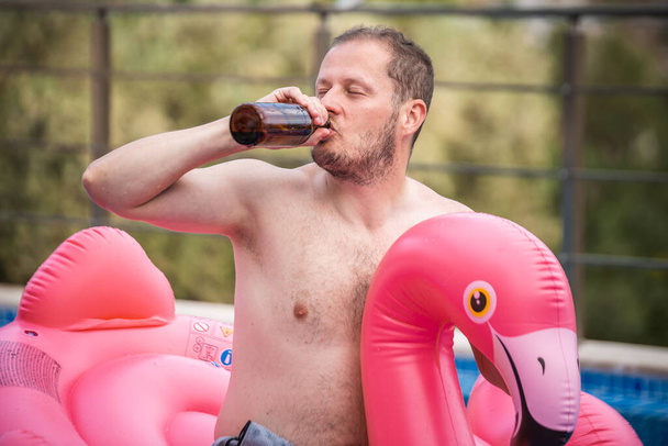 Flamingodaki neşeli adam havuzda eğleniyor. Havuz flamingosunda rahatlayan mutlu bir adam. Seyahat yaz tatili kavramı. - Fotoğraf, Görsel