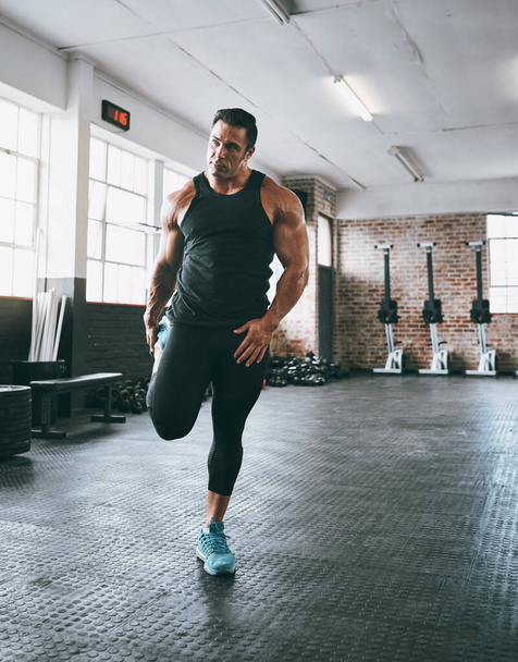 No olvides estirar esos músculos. un joven haciendo ejercicio con pesas en el gimnasio - Foto, Imagen