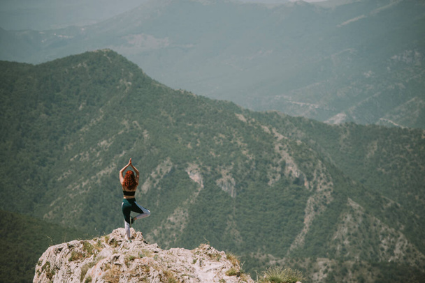 Ragazza di yoga con i capelli rossi ricci facendo alcune pose yoga in cima alla montagna - Foto, immagini