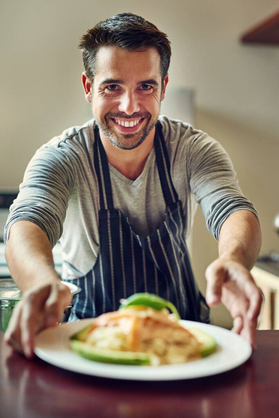 Кулинария это любовь, которую можно есть. молодой человек подает еду на кухне дома - Фото, изображение