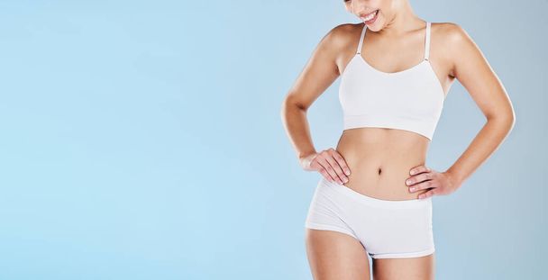 Gesundheit, Körper und Attrappe mit einem Model in Unterwäsche auf blauem Hintergrund im Studio, um für Gewichtsverlust zu werben. Fitness, Wellness und Ernährung mit einer glücklichen Frau, die für einen gesunden Lebensstil posiert. - Foto, Bild