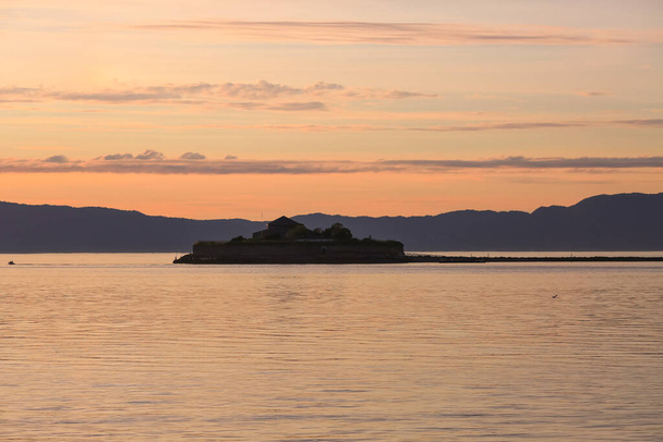 Остров Михольмен, расположенный в Тронхеймском заливе недалеко от города Тронхейм во время заката солнца - Фото, изображение