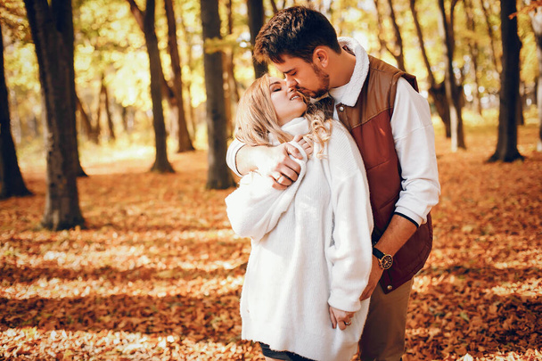 Couple have fun in a autumn park. Cute blode in a white sweater. - Foto, immagini