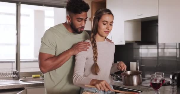 Love, couple and cooking food taste test of happy partner in home kitchen for romantic lunch date. Happiness, house and interracial people dating talk and smile while preparing meal with wine - Footage, Video