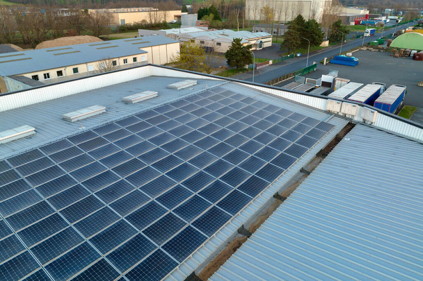 Letecký pohled na modré fotovoltaické solární panely namontované na střeše průmyslové budovy pro výrobu zelené ekologické elektřiny. Výroba koncepce udržitelné energie. - Fotografie, Obrázek