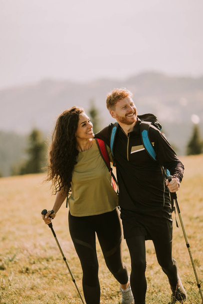 Sorridente giovane coppia a piedi con zaini su verdi colline - Foto, immagini
