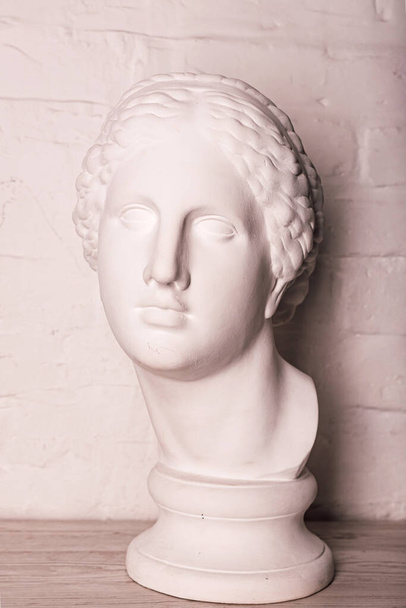 Tynkowa głowa posągu na tle białej ceglanej ściany. Wysokiej jakości zdjęcie - Zdjęcie, obraz