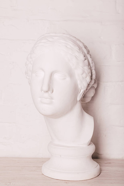 A szobor vakolatfeje egy fehér téglafal hátterében. Kiváló minőségű fénykép - Fotó, kép