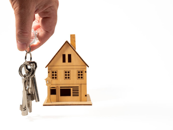 House key in hand on the background of a wooden house. The concept of buying a house. - Photo, Image