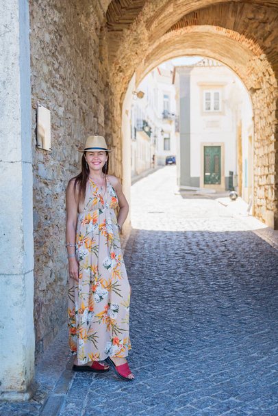 Portrait of an attractive tourist woman in old town Wearing stylish long dress, bracelets and straw hat. - Fotografie, Obrázek