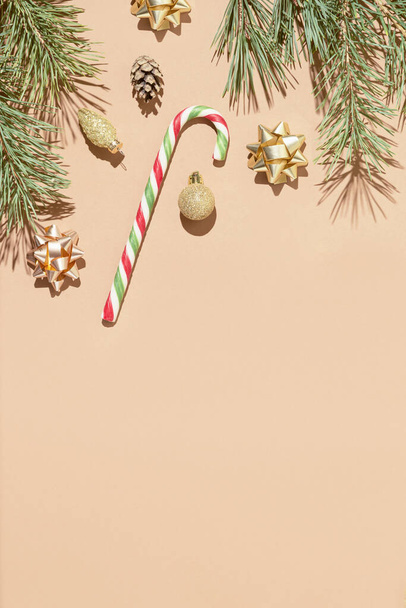 Winter compositie gemaakt van sparren takken, lolly en kerst decoratie op pastel beige achtergrond. Kerstmis en nieuwjaarsconcept. Plat gelegd. Bovenaanzicht, kopieer ruimte. - Foto, afbeelding