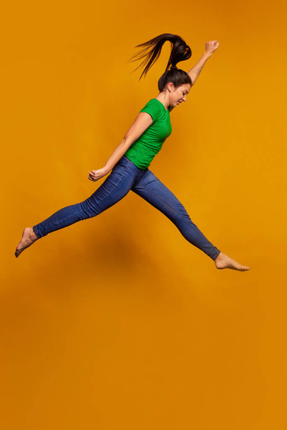 Freestyle. Happy young girl, student jumping isolated on bright yellow background. Concept of beauty, art, summer fashion, human emotions and facial expressions. Copy space for ad - Φωτογραφία, εικόνα