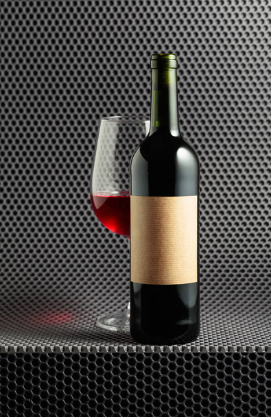 Bottle and glass of red wine on a grey cellular background. - Fotó, kép