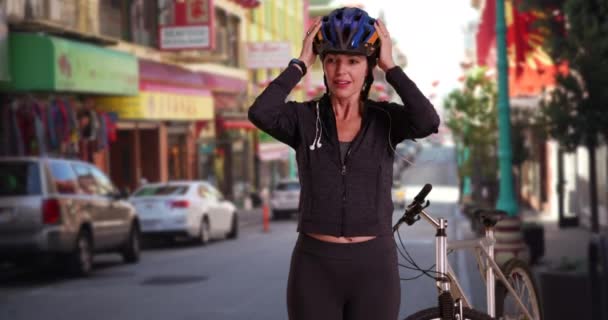 Femme caucasienne d'âge moyen utilisant l'appareil après l'entraînement avec le vélo à Chinatown, San Francisco. Femme blanche debout avec exercice de poste de vélo sur la rue de la ville urbaine. 4k - Séquence, vidéo