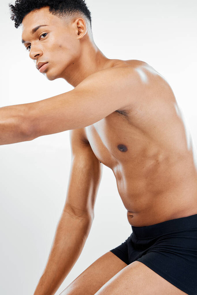 体のケアのための白い背景を持つスタジオで黒人男性のフィットネス、健康と健康的な体。減量と食事療法です。筋肉、強さと腹筋のための下着にワークアウト、運動と黒の男ポーズ. - 写真・画像