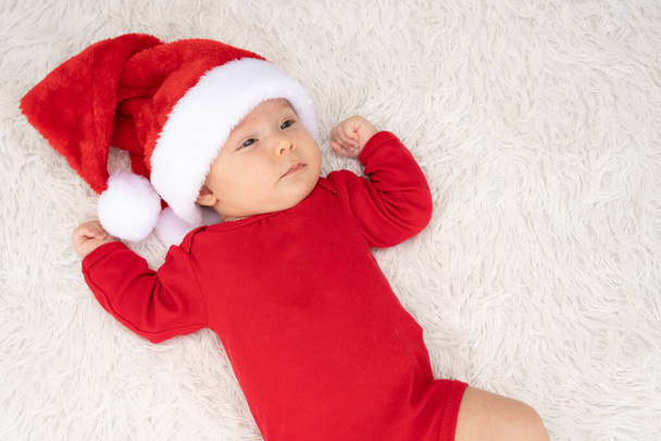 roztomilý novorozeně dítě dívka s Santa klobouk ležící venku - Fotografie, Obrázek