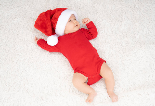 cute newborn baby girl with santa hat lying outdoors - Photo, image