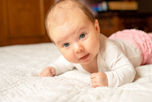 Bebé recién nacido en manta de textura, acostado en la cama ojos abiertos. - Foto, Imagen