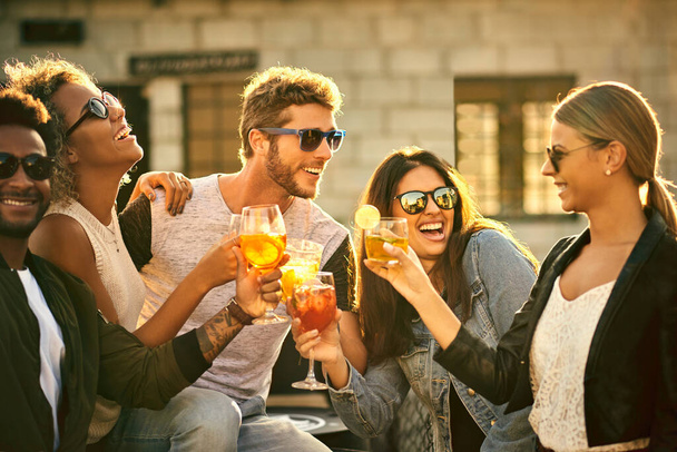 Järjestä aikaa hauskanpitoon. ryhmä nuoria ystäviä hengailemassa ja drinkillä ulkona - Valokuva, kuva