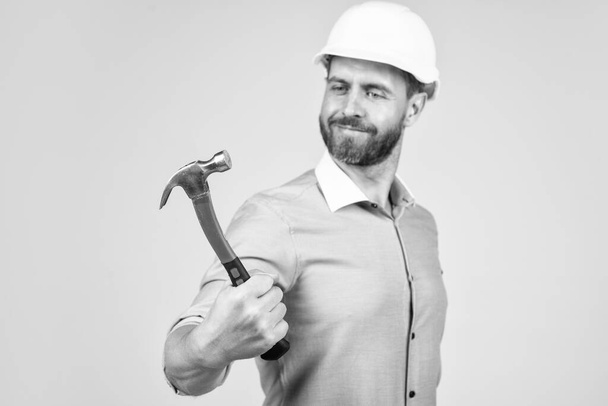 handsome smiling bearded businessman in helmet hold hammer, repairing. - Photo, image