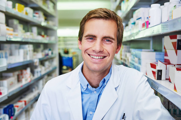 Keeping you well keeps me happy. Portrait of a confident young pharmacist working in a pharmacy - Foto, afbeelding