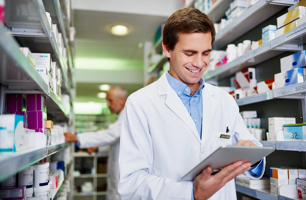 Gérer efficacement les pharmacies sont juste une application loin. un jeune pharmacien utilisant une tablette numérique dans une pharmacie - Photo, image