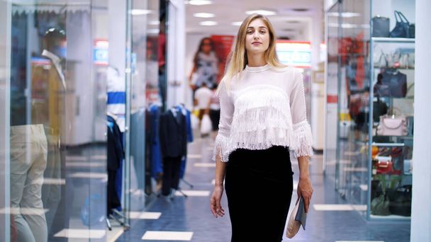 Sexy girl, tall, beautiful blond woman walking down the hall of shopping center, along the windows of shops and stylish boutiques. Shopping in a stylish clothing stores. High quality photo - Foto, afbeelding