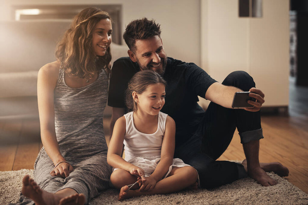 Lach als je van je familie houdt. een gelukkig jong gezin neemt een selfie samen thuis - Foto, afbeelding