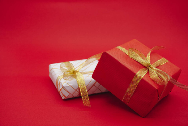 Rot-weißer Geschenkkarton mit goldenen Bändern. Weihnachtsgeschenkbox. Vereinzelt auf rotem Hintergrund. - Foto, Bild