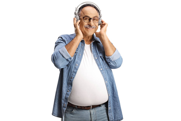 Веселый зрелый мужчина с наушниками, слушающий музыку на белом фоне - Фото, изображение