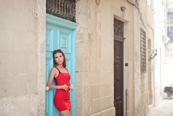 young woman leaning against a door of a house - 写真・画像