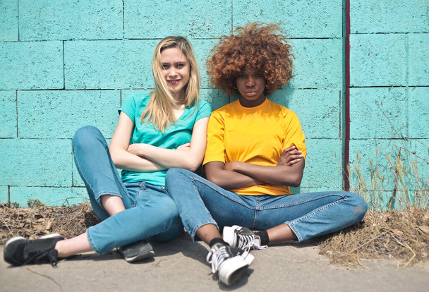 portrait of two young women leaning against a colorful wall - Foto, afbeelding