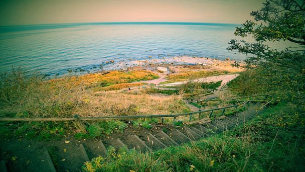 Ścieżka schodami na plażę przylądka Arkona klif kredowy na Bałtyku. Jesienna pogoda i morze w długiej ekspozycji - Zdjęcie, obraz
