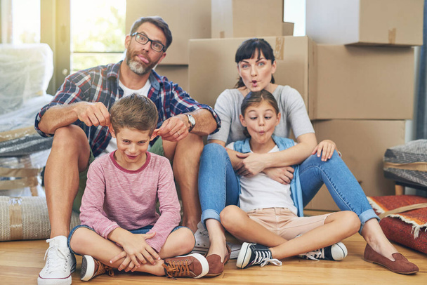 Were all crazy here. Portrait of a happy family making funny faces together in their home on moving day - Photo, Image