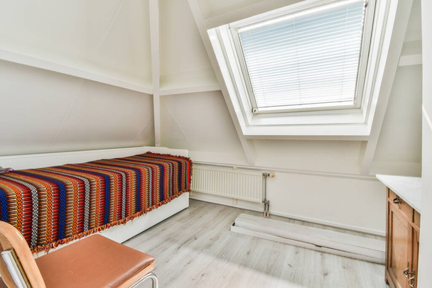 Komfortní postel umístěna v blízkosti zdi v moderním minimalistickém stylu mansard ložnice s okny - Fotografie, Obrázek