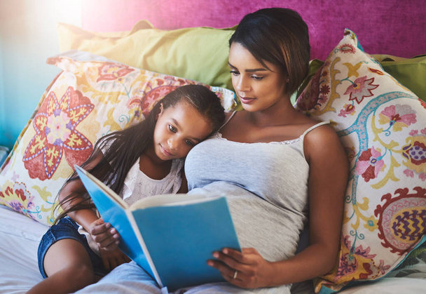 Feed their minds with good books. a mother reading a story to her little daughter at home - Foto, imagen