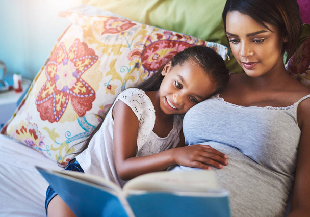 Her love for reading started with Mom. a mother reading a story to her little daughter at home - Foto, imagen