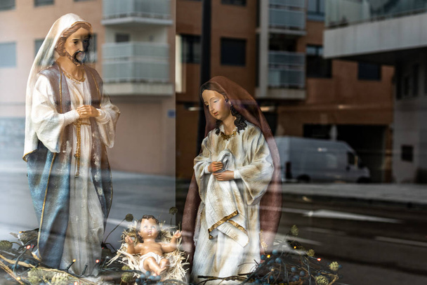 hermosas figuras grandes de santos del belén para Navidad, cerca del reflejo de la ciudad en el cristal - Foto, Imagen