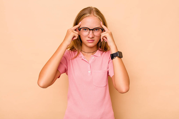 Caucasien adolescent fille isolé sur fond beige concentré sur une tâche, en gardant les index pointant la tête. - Photo, image