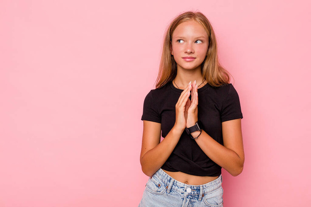 blank tiener meisje geïsoleerd op roze achtergrond maken van plan in het achterhoofd, het opzetten van een idee. - Foto, afbeelding