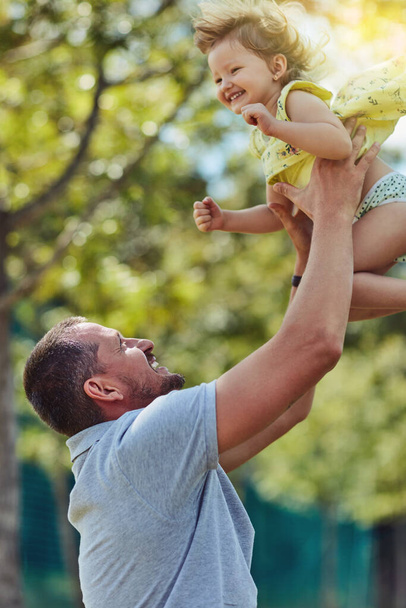 Дайте им крылья, чтобы достичь их мечты. Отец сближается со своей маленькой дочкой на открытом воздухе - Фото, изображение
