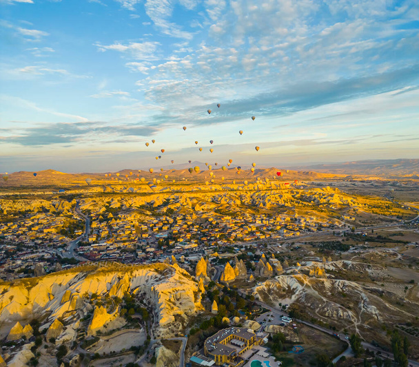 Early morning. Many hot air balloons high in the sky in the sunlight flying over Cappadocia, the city and fairy chimneys in Turkey. High quality photo - Zdjęcie, obraz