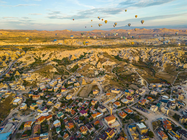 Breathtaking drone view of hundreds of hot air balloons ride over Turkeys iconic Cappadocia, the city in the middle of fairy chimneys valley during the sunrise. High quality photo - Фото, изображение