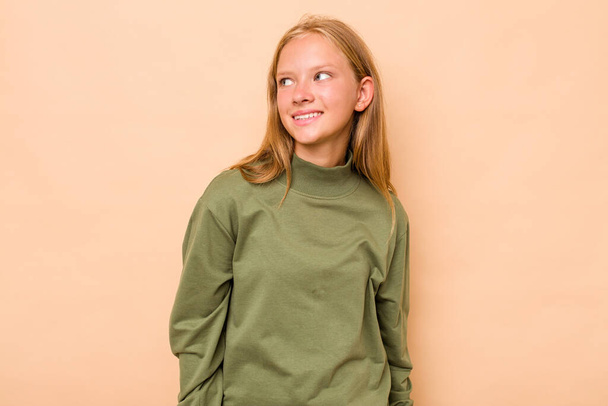 Caucasian teen girl isolated on beige background relaxed and happy laughing, neck stretched showing teeth. - Photo, Image